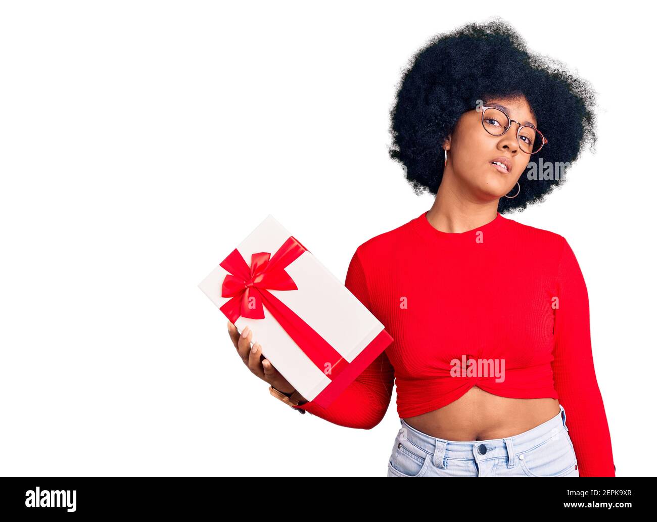 Young african american girl holding gift looking sleepy and tired, exhausted for fatigue and hangover, lazy eyes in the morning. Stock Photo