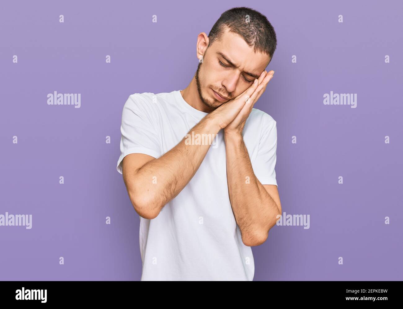 Hispanic young man wearing casual white t shirt sleeping tired dreaming ...