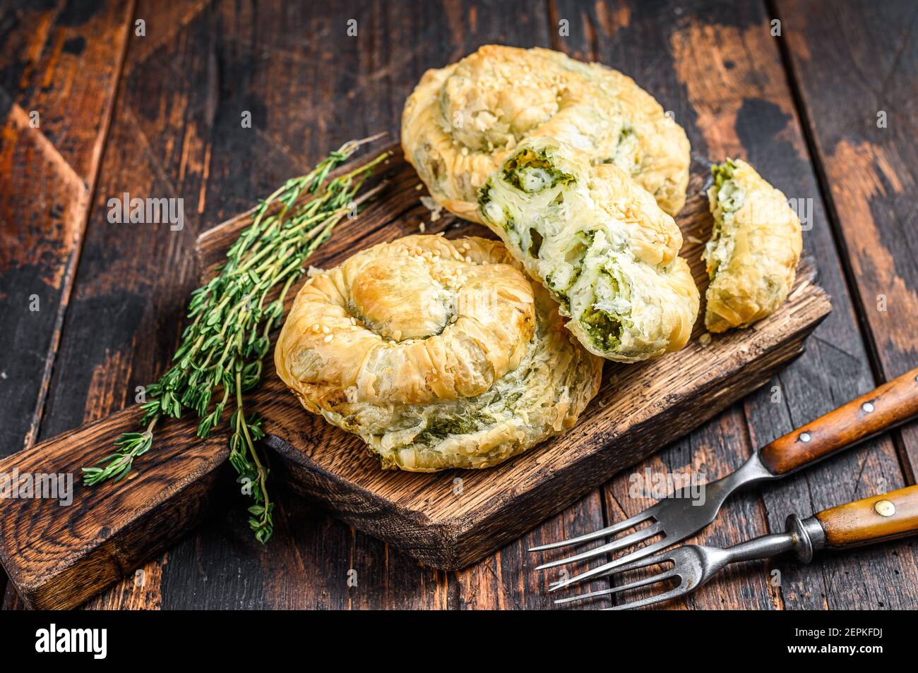 Baked spiral filo pastry puff with feta cheese and spinach. Dark wooden