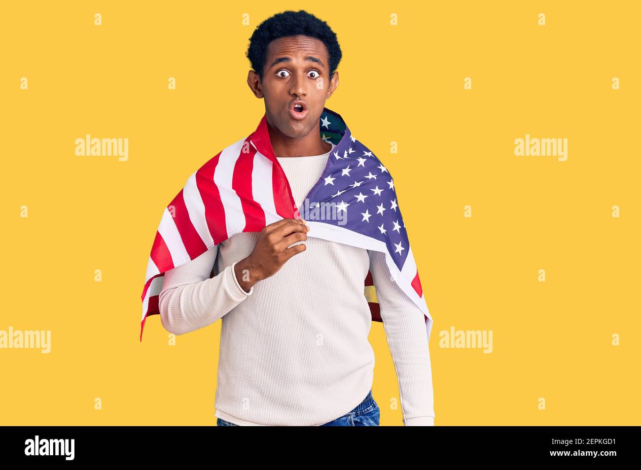 African handsome man holding united states flag scared and amazed with ...