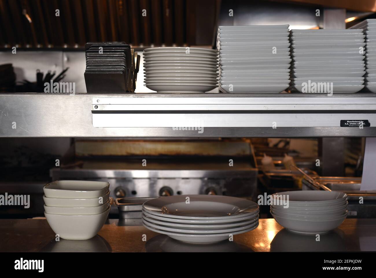Dishes of various sizes and shapes line a counter in a kitchen in a restaurant Stock Photo