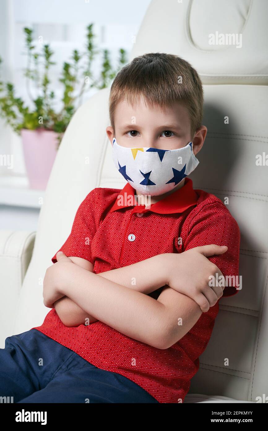 Little boy patient wearing a protective face mask sitting in a medical ...
