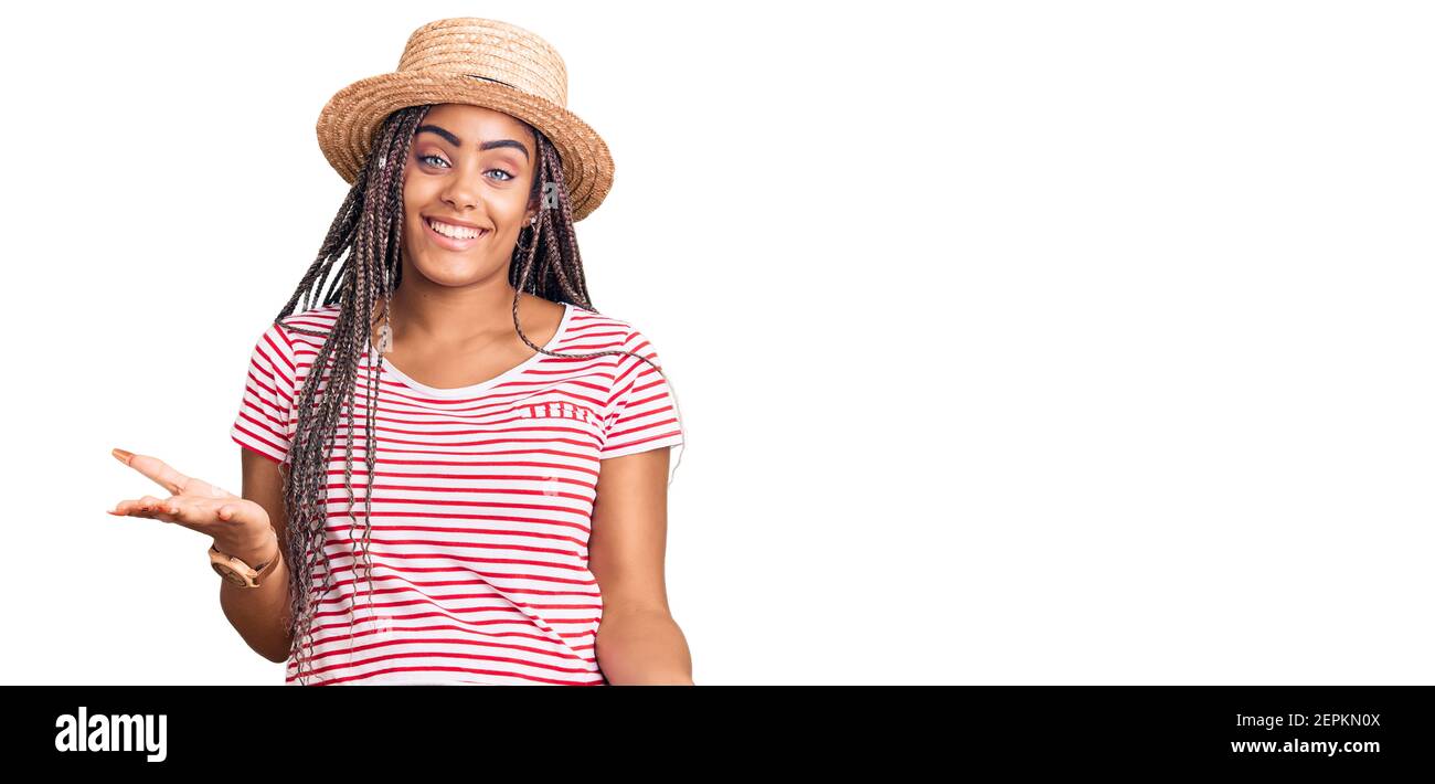 Young african american woman with braids wearing summer hat smiling ...