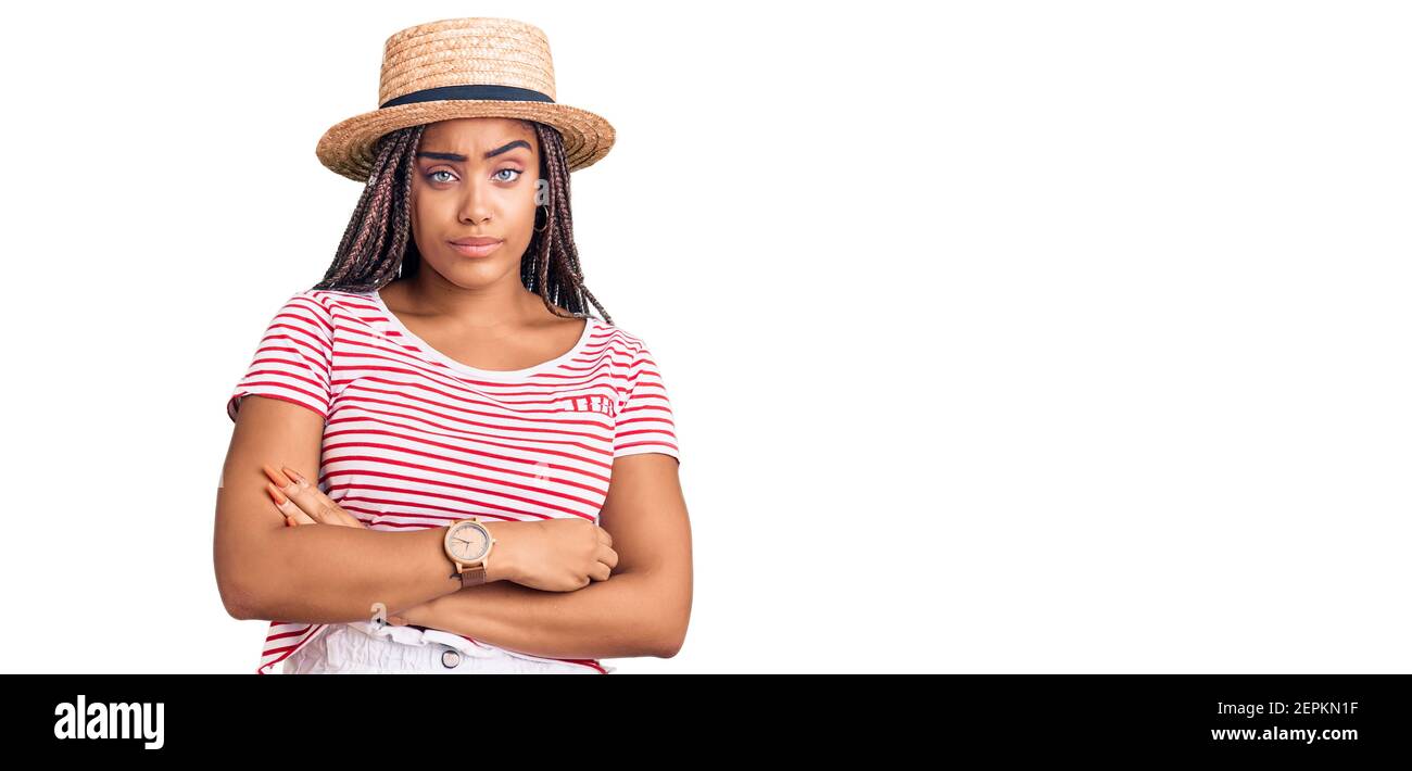 Young african american woman with braids wearing summer hat looking sleepy and tired, exhausted for fatigue and hangover, lazy eyes in the morning. Stock Photo