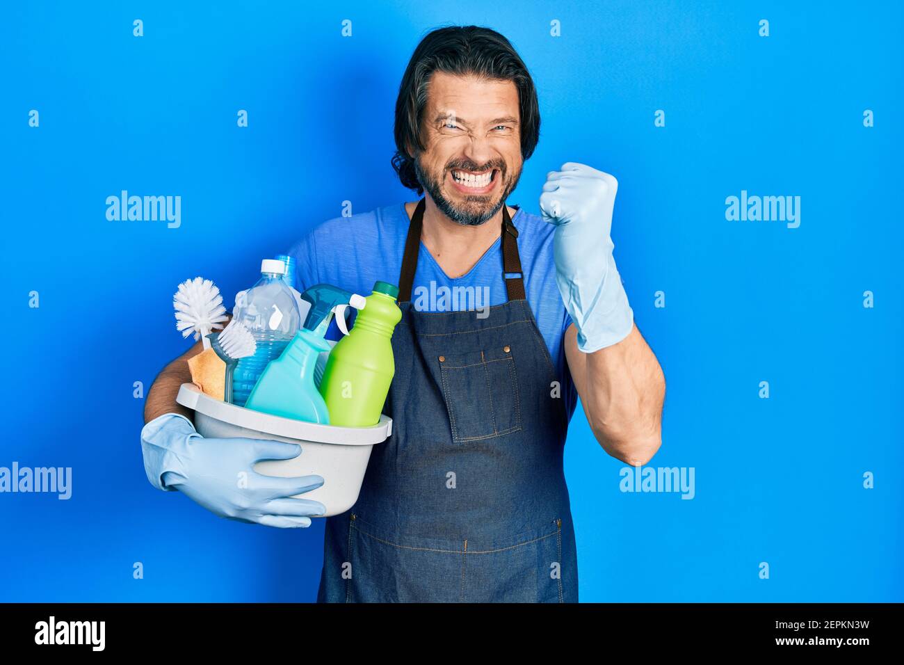 Middle age caucasian man holding cleaning products annoyed and frustrated shouting with anger, yelling crazy with anger and hand raised Stock Photo