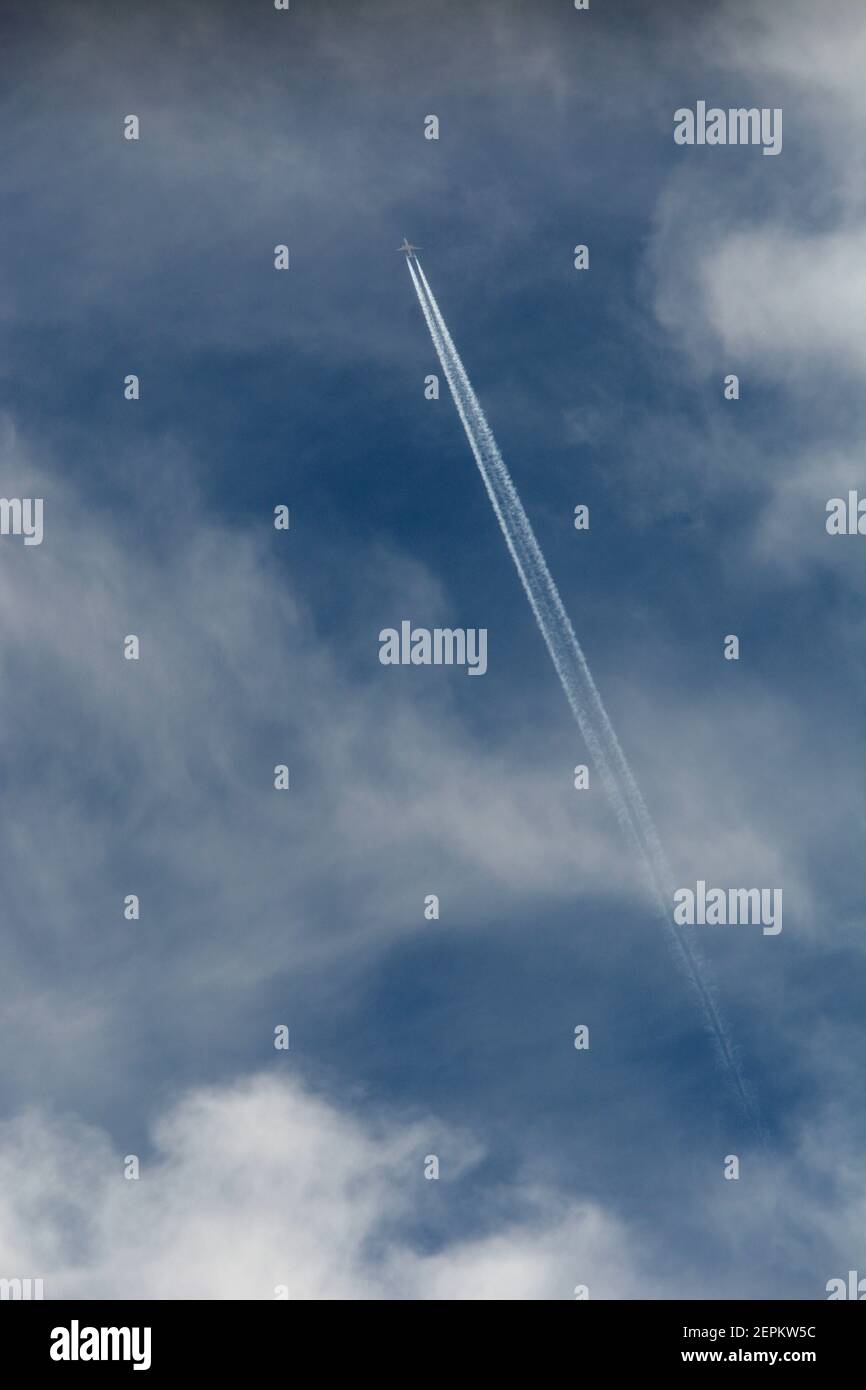 A commercial jet passenger airplane  leaves a contrail in its wake as it flies through the clouds over the American Southwest. Stock Photo