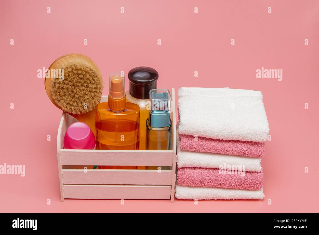 Flat lay composition with spa cosmetics and towel on pink background ...