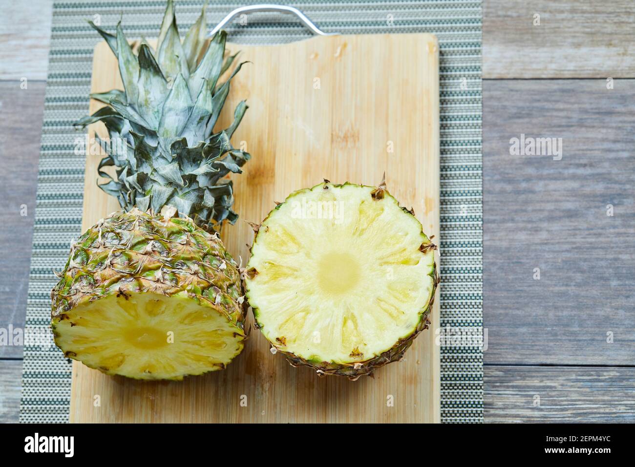 A pineapple sliced into half on wooden board Stock Photo
