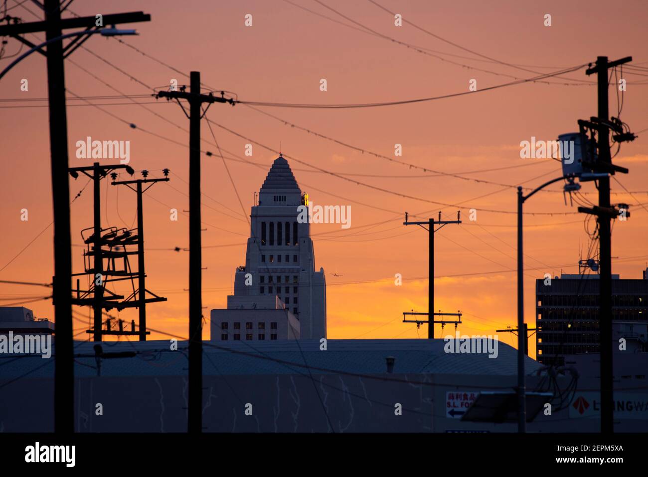 gritty sunset view of Los Angeles city hall building through power lines at sunset Stock Photo