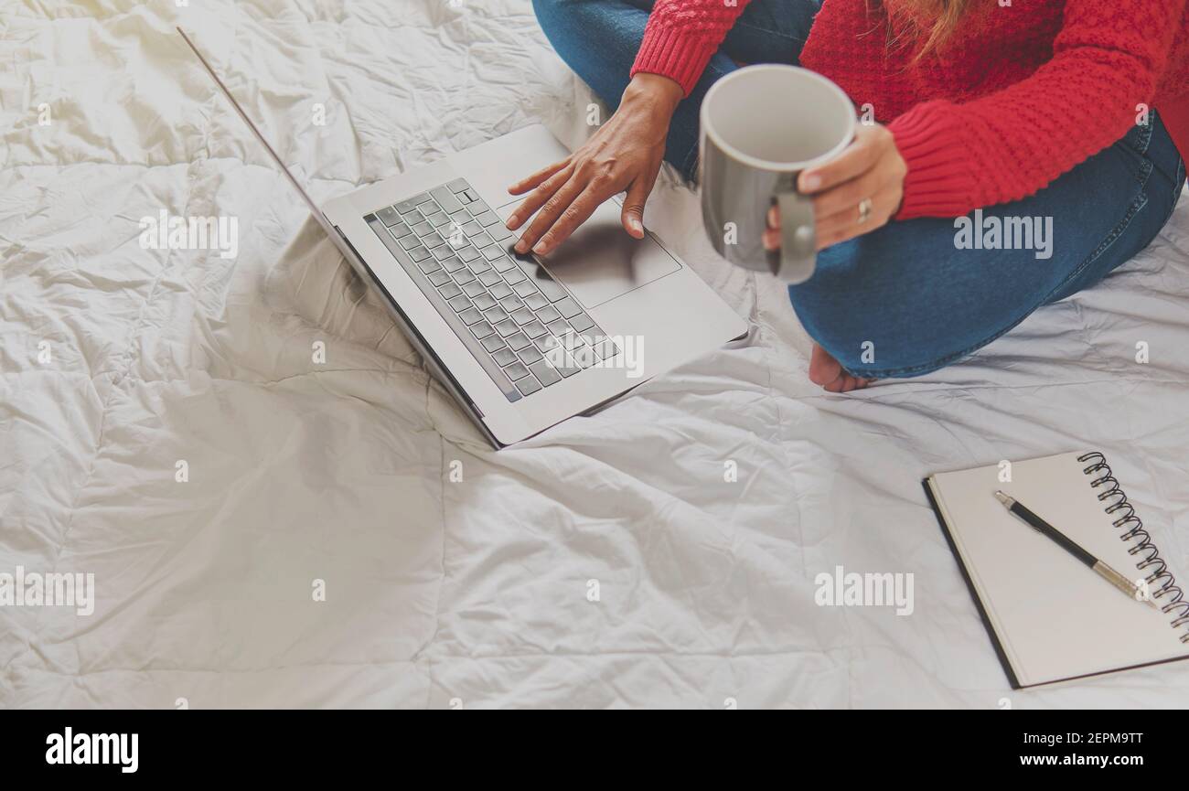 Portrait of a Latin woman drinking hot coffee and using laptop, watching video, free space photo picture