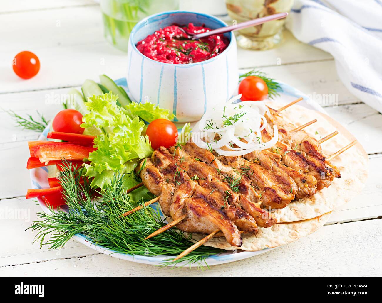 Grilled chicken kebab with beet hummus and pita, fresh vegetables on a