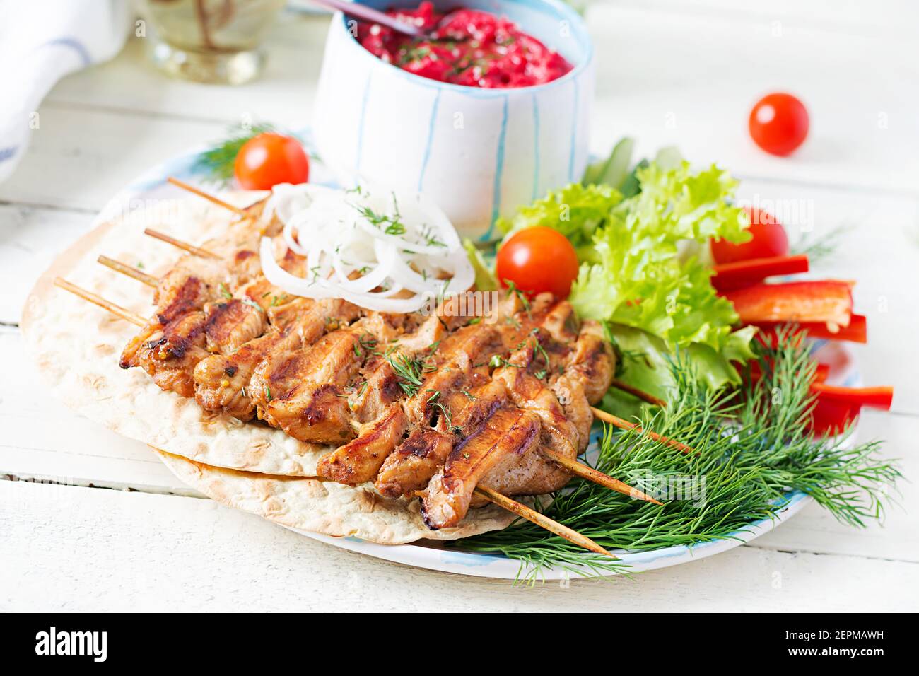 Grilled chicken kebab with beet hummus and pita, fresh vegetables on a
