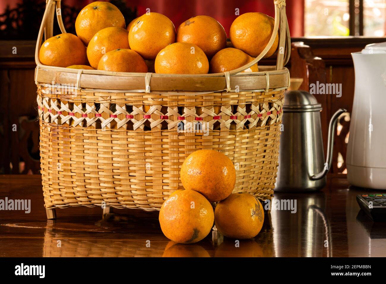 Ripe oranges in a bamboo basket on a wooden table. Stock Photo
