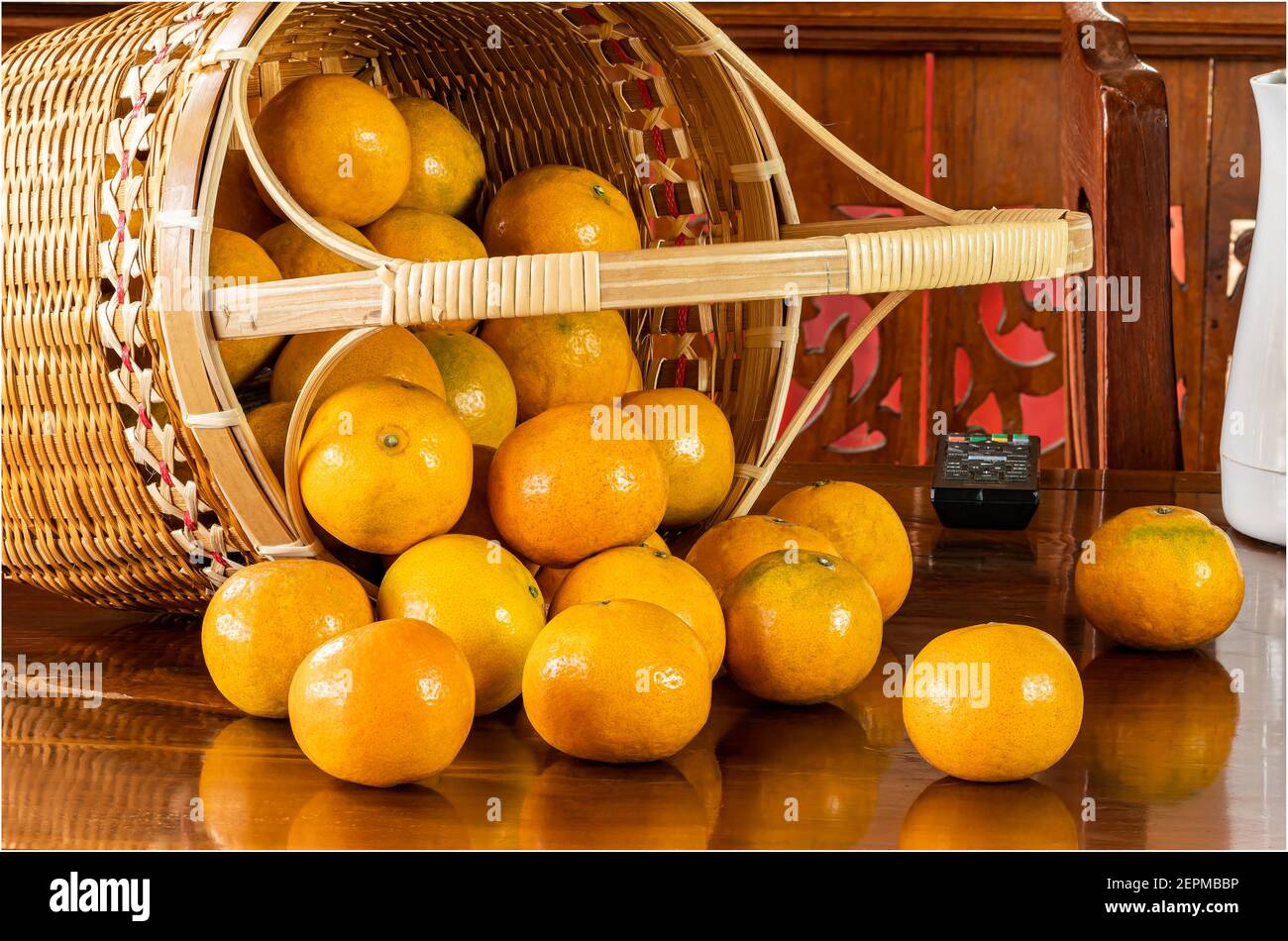 View of oranges in a bamboo basket on wooden table. Stock Photo