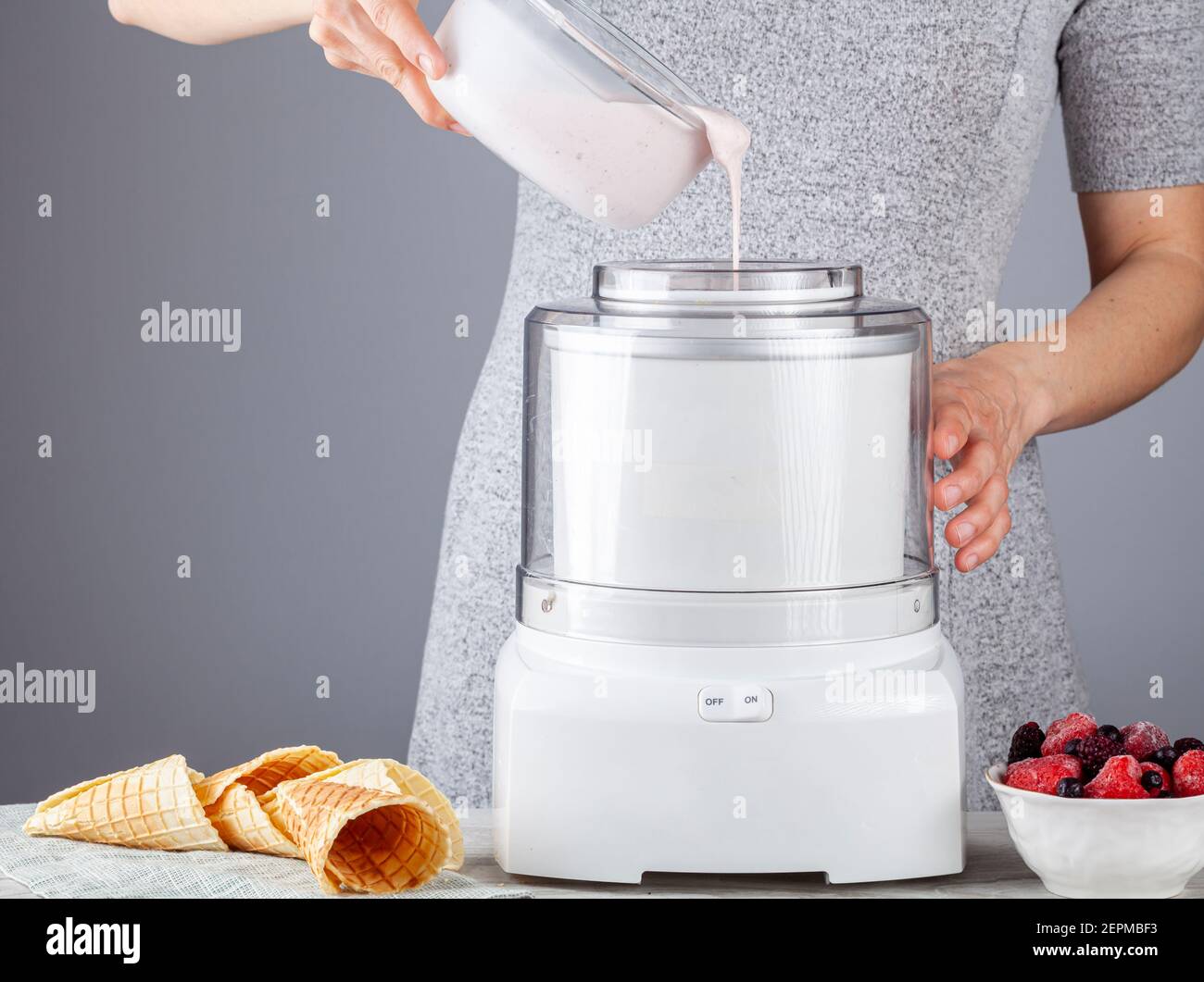 A caucasian woman is pouring homemade all natural ice cream mixture into an ice cream maker machine. Berry and strawberries were added to add flavor. Stock Photo