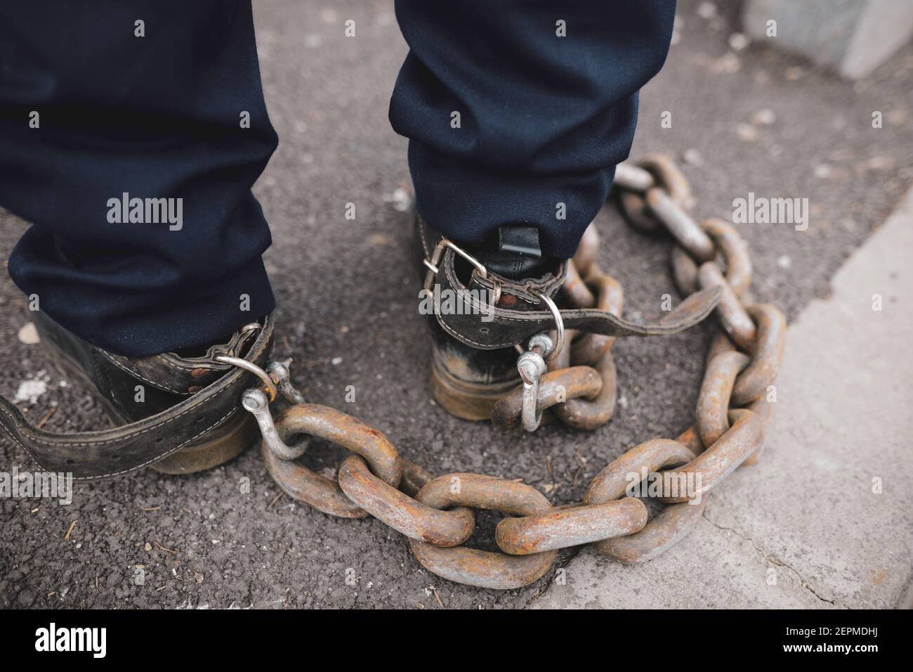 Shallow depth of field (selective focus) details of a policeman who tied a rusty metal chain to his feet during a protest in Bucharest. Stock Photo