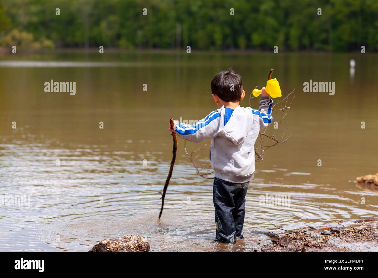 An active little preschooler boy is playing in shallow water in the small lake at the Catoctin Mountains. His pants are soaked up wet but still playin Stock Photo