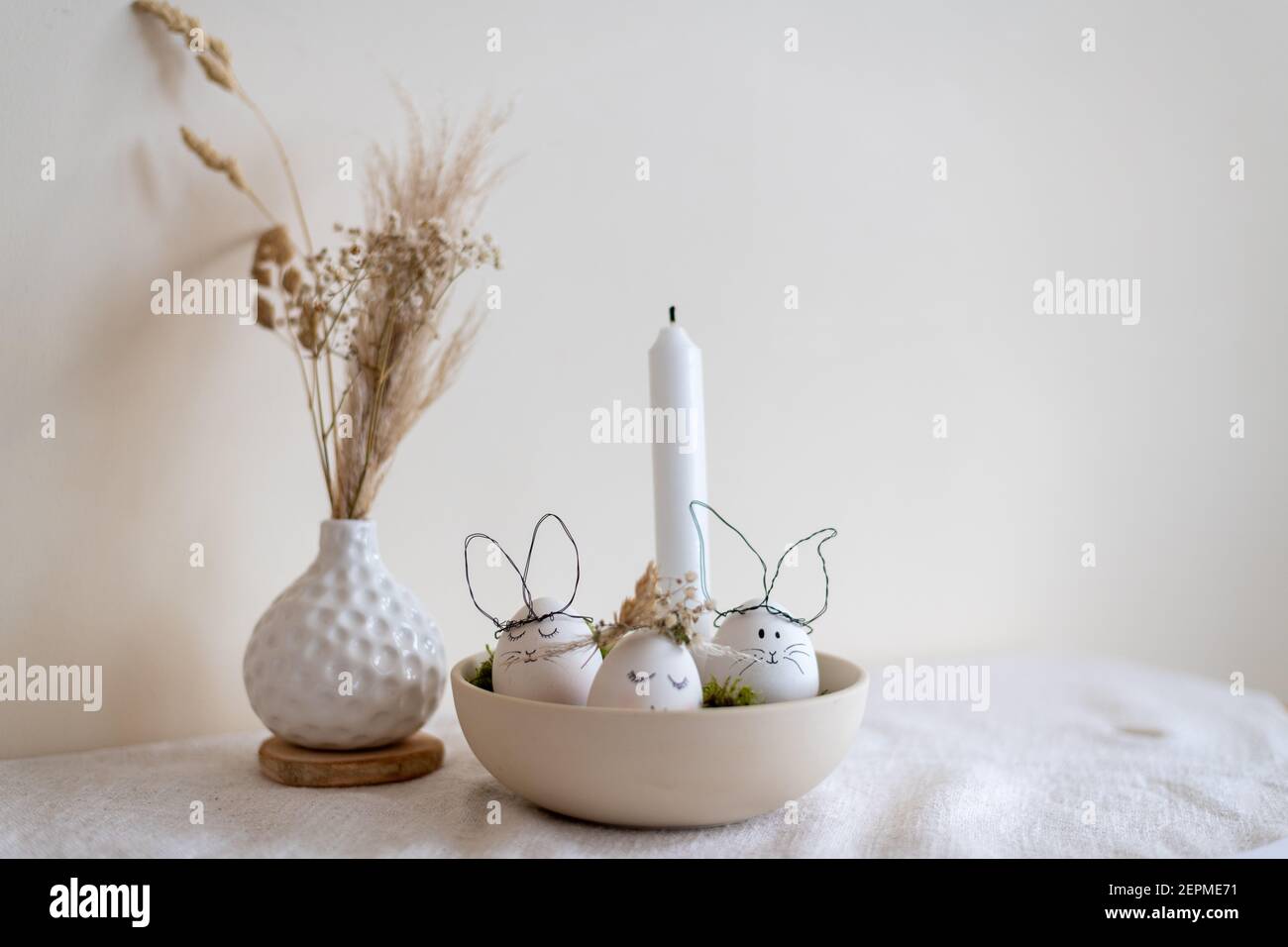 3 eggs as decoration for Easter, 2 as bunnies one as a girl with a flower wreath in a bowl. Happy Easter. Stock Photo
