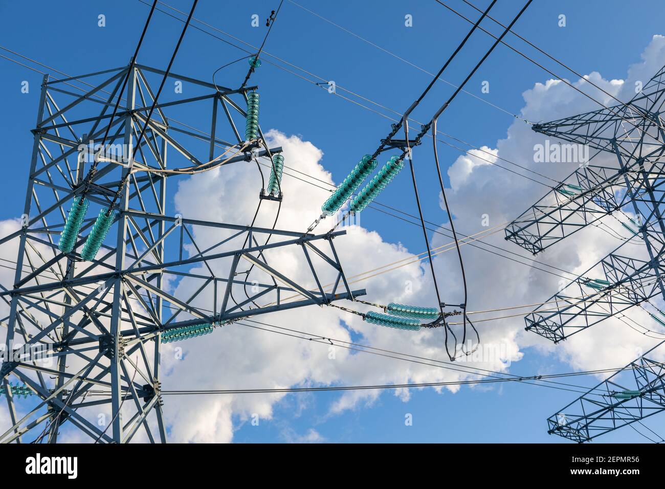 New large mast of an air power line close up, high voltage electricity pylon with thick wires and insulators, blue sky on background. Traditional Stock Photo