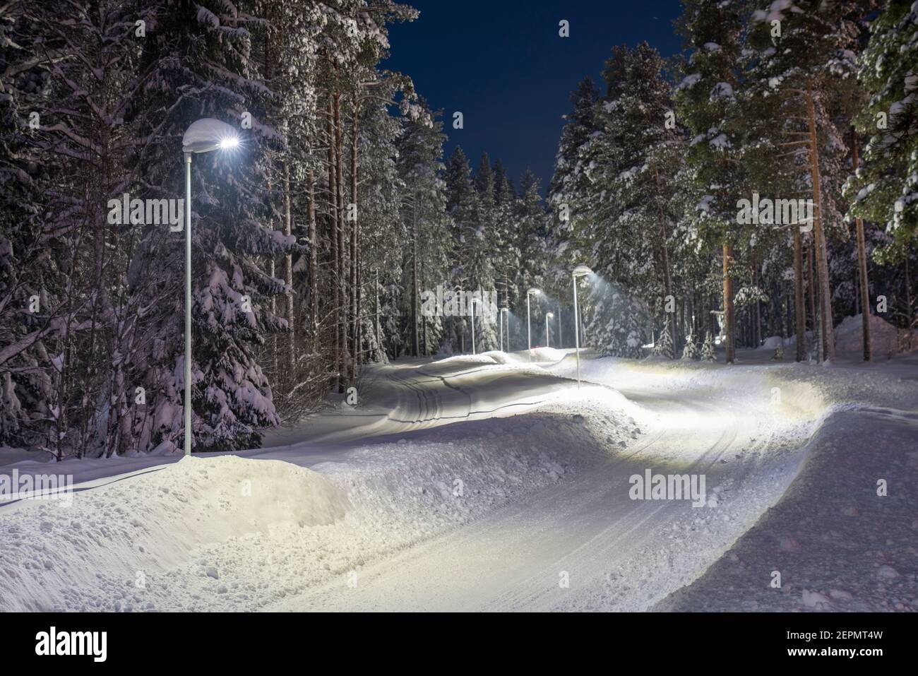 Snow-covered and plowed walkway illuminated with street light in Pitea Stock Photo
