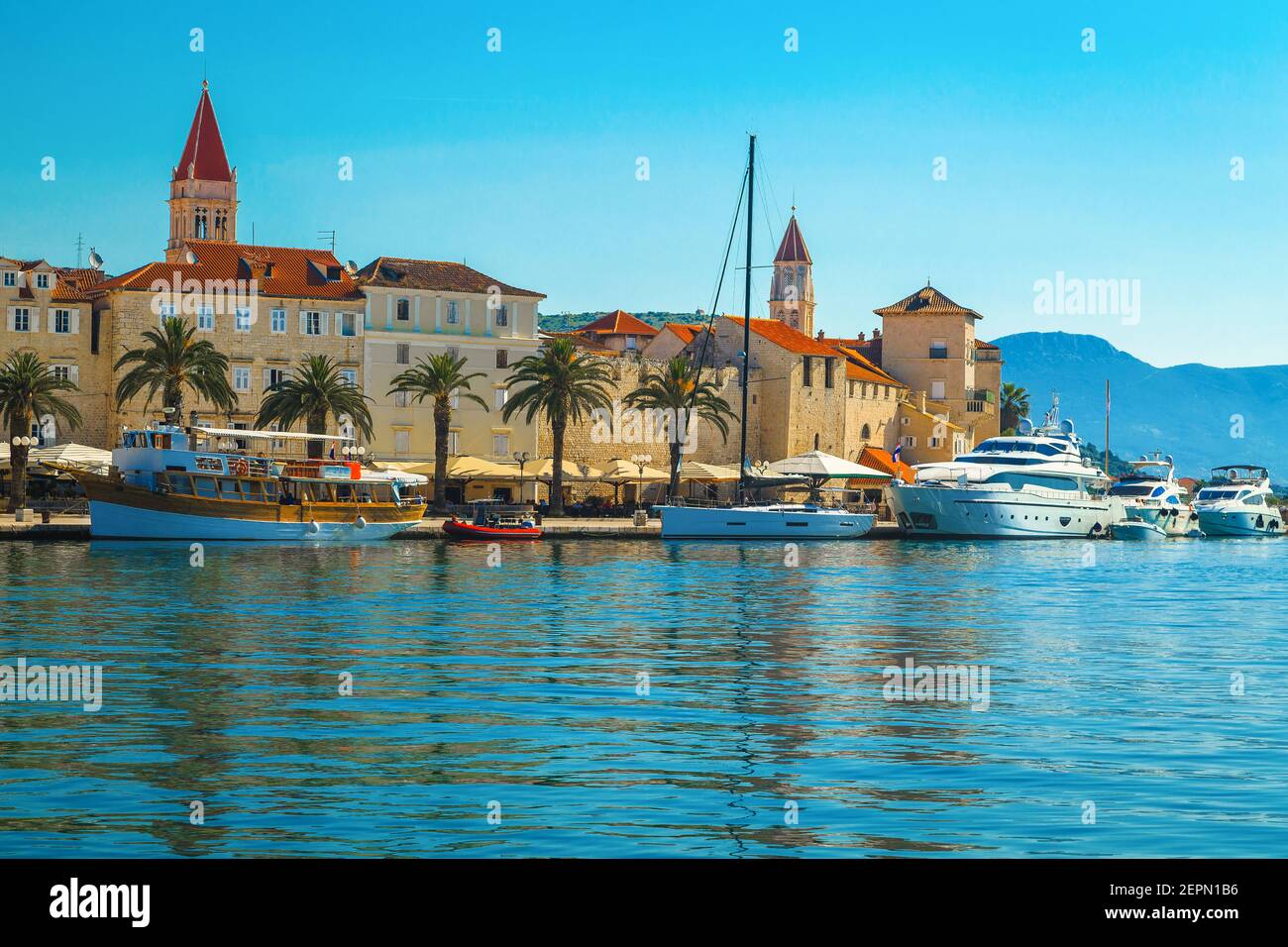 Beautiful view with luxury yachts and boats in the touristic harbor. Popular waterfront promenade with palms and street cafes, Trogir, Dalmatia, Croat Stock Photo