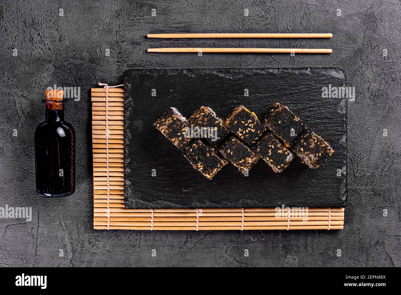 Sushi roll with salmon, avocado and cheese on a black stone plate on a white plate. Sushi menu. Japanese food. black rice sushi Stock Photo