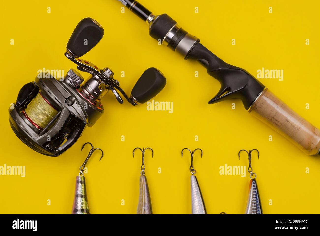 Fishing rod baitcasting reel and baits on a yellow background