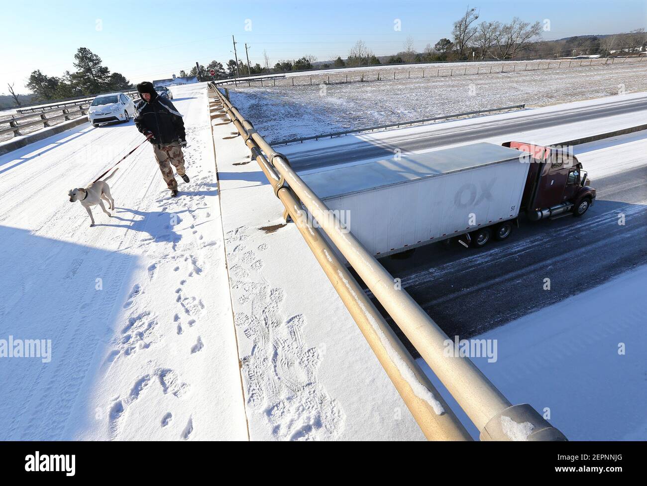 A tractor trailer is stuck in the ice while Paul Vaca walks his dog Casper across an ice covered overpass. All westbound lanes on I-20 were closed at the Almon Road exit after multiple tractor trailer trucks jackknifed in the winter conditions on Wednesday, January 17, 2018, in Covington, Ga. (Photo by Curtis Compton/Atlanta Journal-Constitution/TNS/Sipa USA) Stock Photo