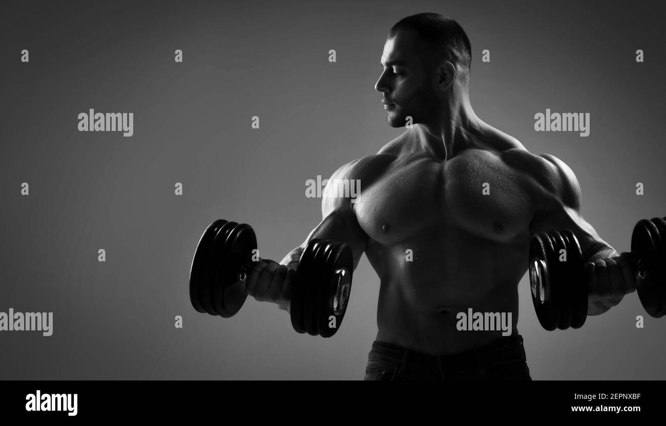 Closeup of a muscular strong well built men bodybuilder lifting dumbbell weights get ready for