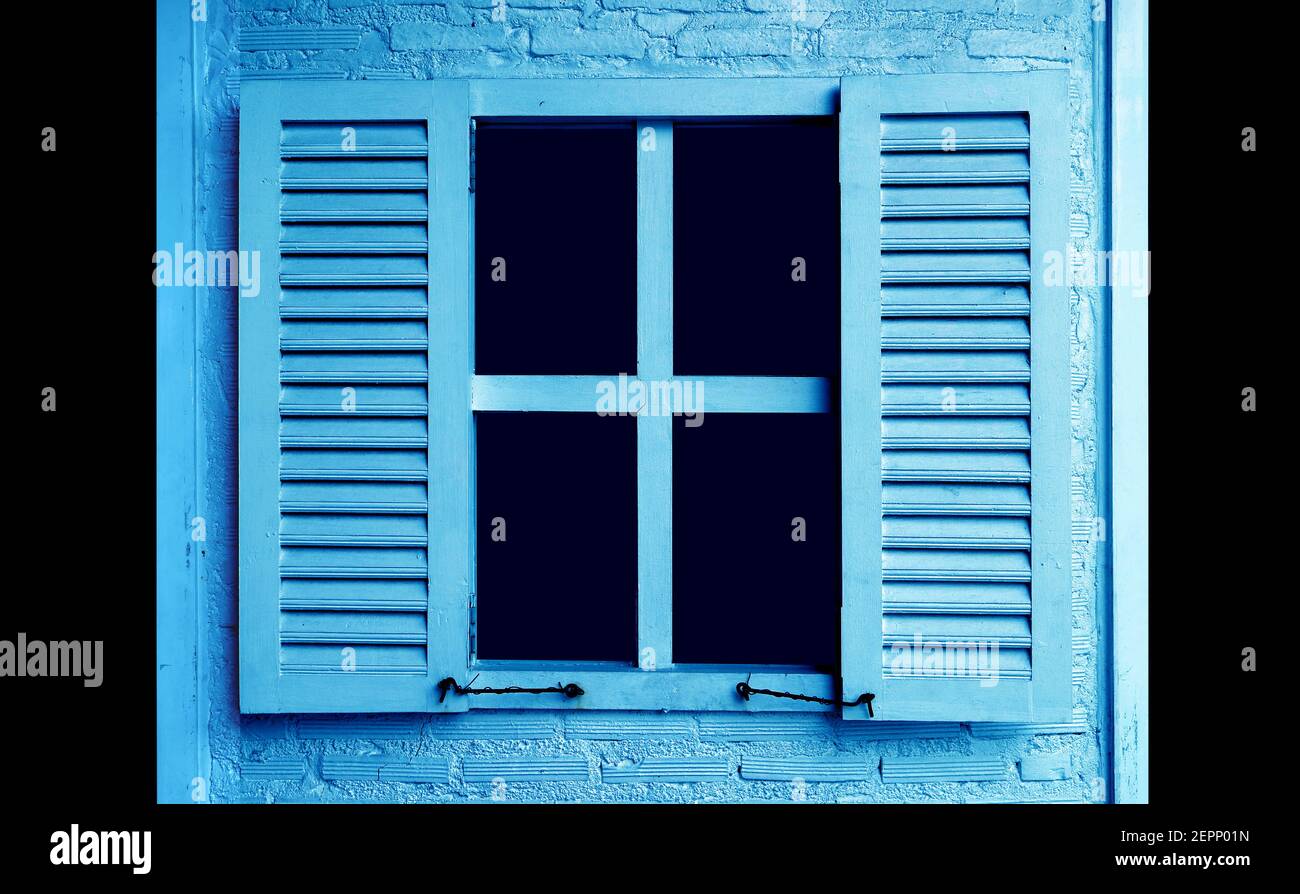 Sky blue colored wooden window with the opening shutters on brick wall Stock Photo
