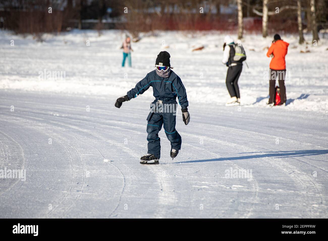 Young person skating on natural ice of frozen Laajalahti Bay in Munkkiniemi district of Helsinki, Finland Stock Photo