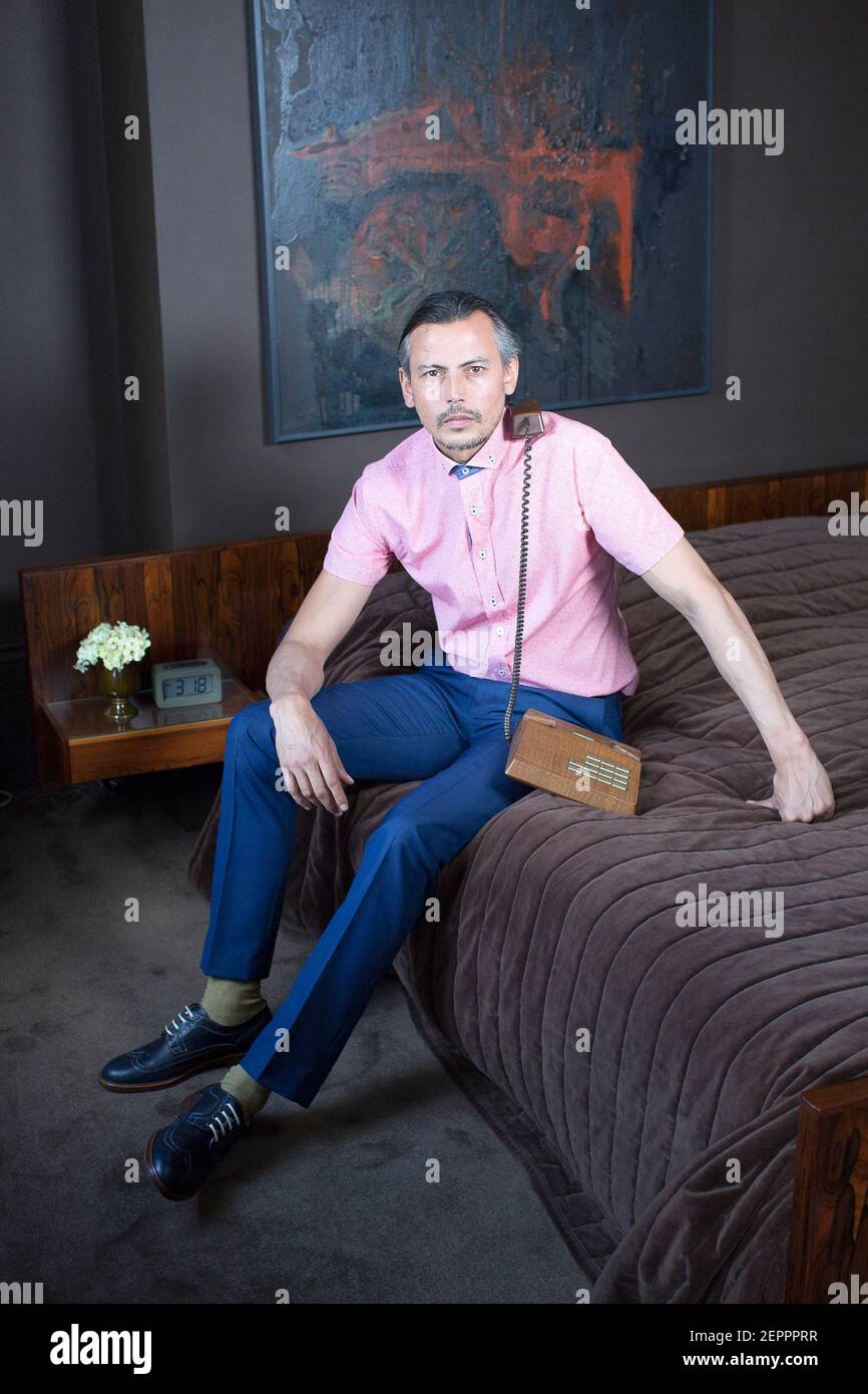 Male model fashion shoot in hotel suite with vintage telephone Stock Photo
