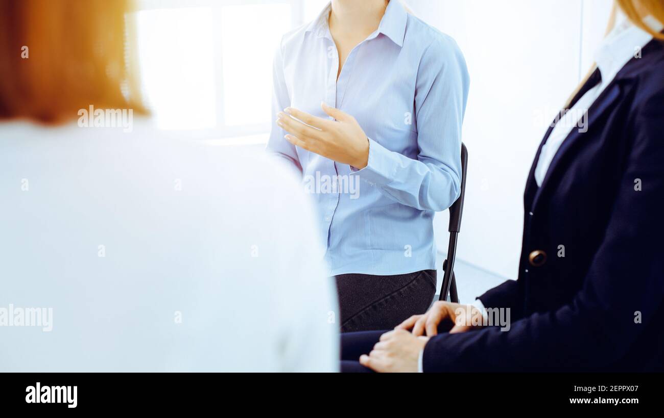 Group of people sitting in a circle during therapy in office. Meeting of business team participating in training Stock Photo