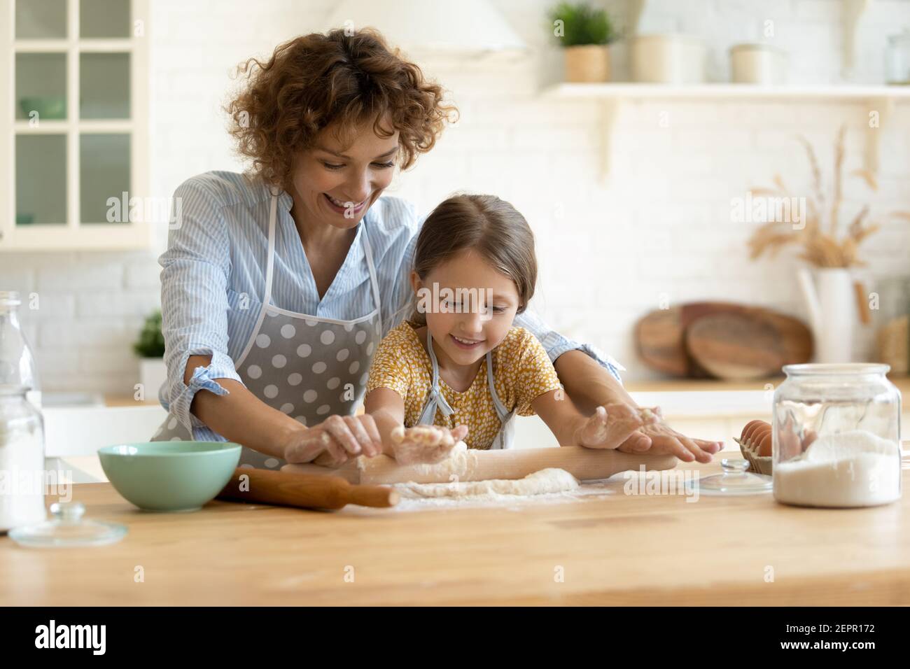 Happy young mom bake with kid roll dough at kitchen Stock Photo