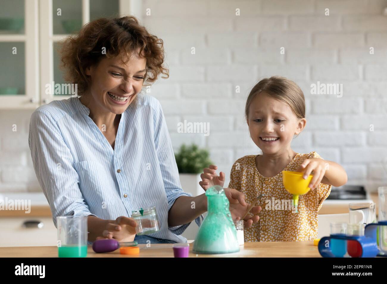 Emotional mother and daughter kid doing chemical experiments at kitchen Stock Photo