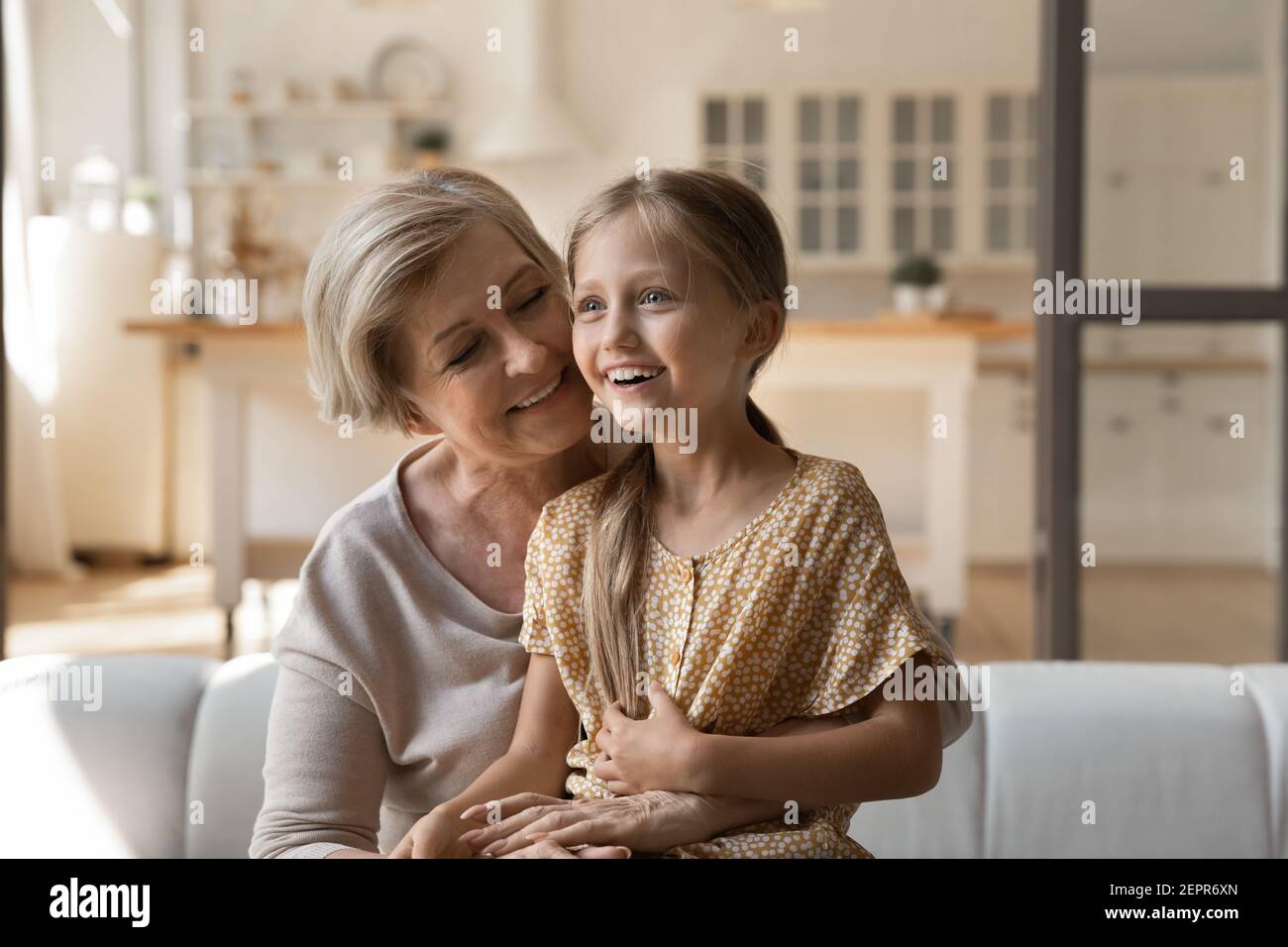 Excited little girl grandchild sit on loving mature grandmother knees Stock Photo