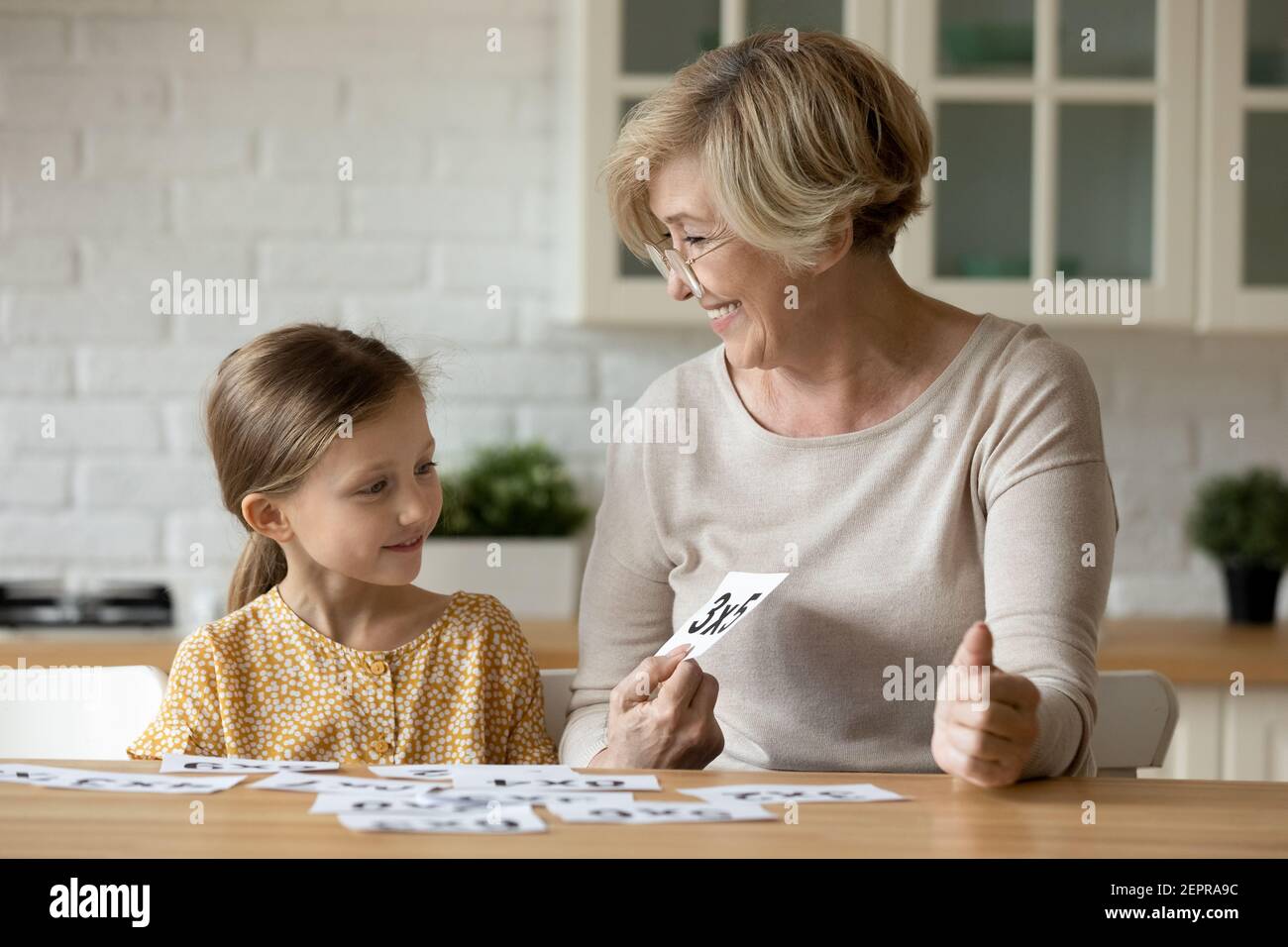 Aged woman teacher study math with pupil girl using cards Stock Photo