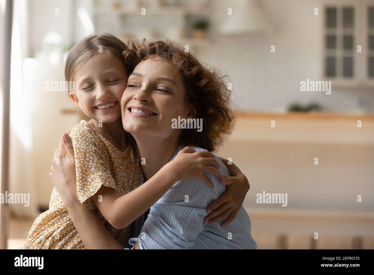 Happy foster mother and adopted daughter hug tight touch cheeks Stock Photo