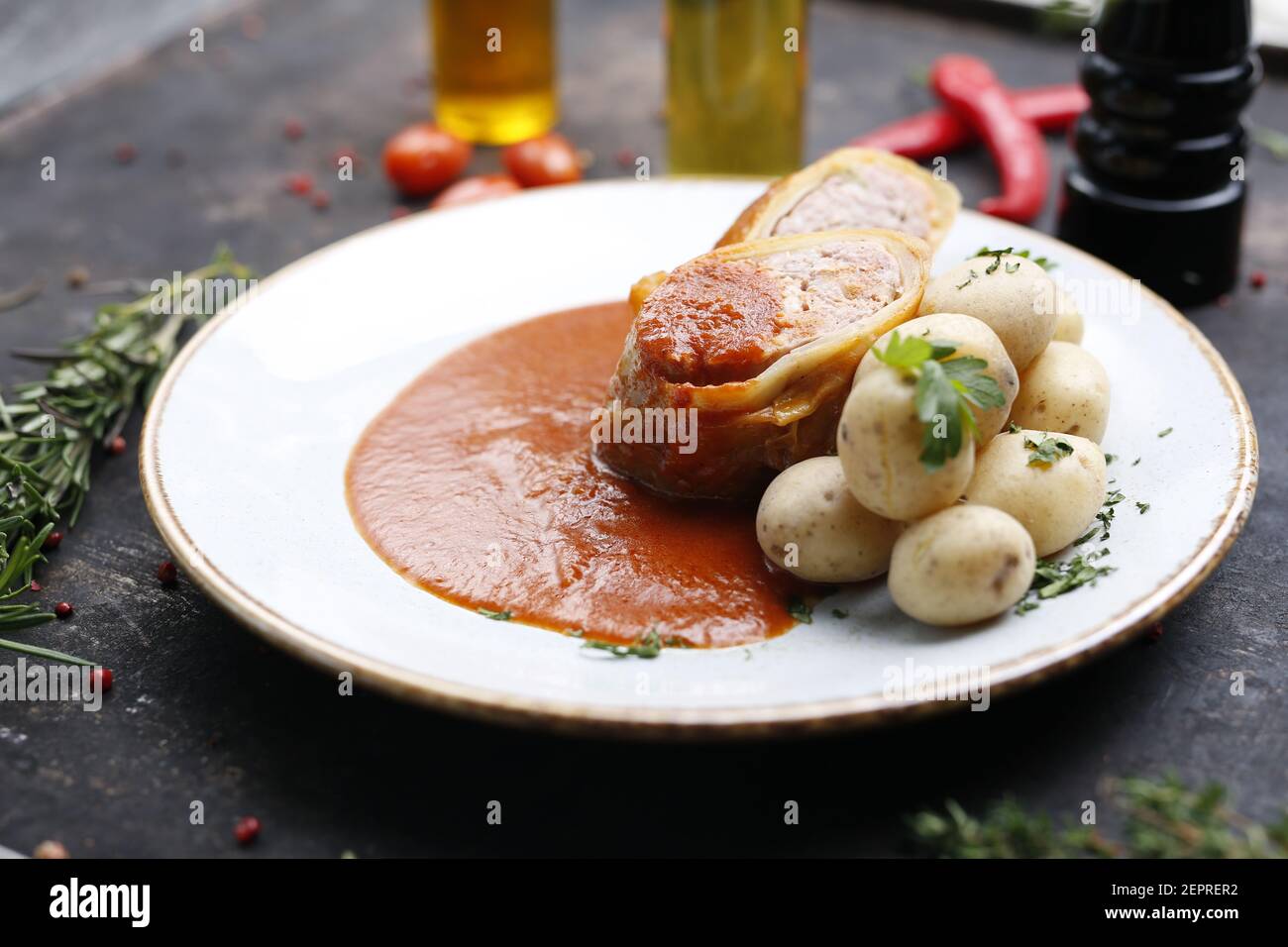 Stuffed cabbage with minced meat in tomato sauce served with potatoes. Ready dish served on a plate. Serving proposal, culinary photography. Stock Photo