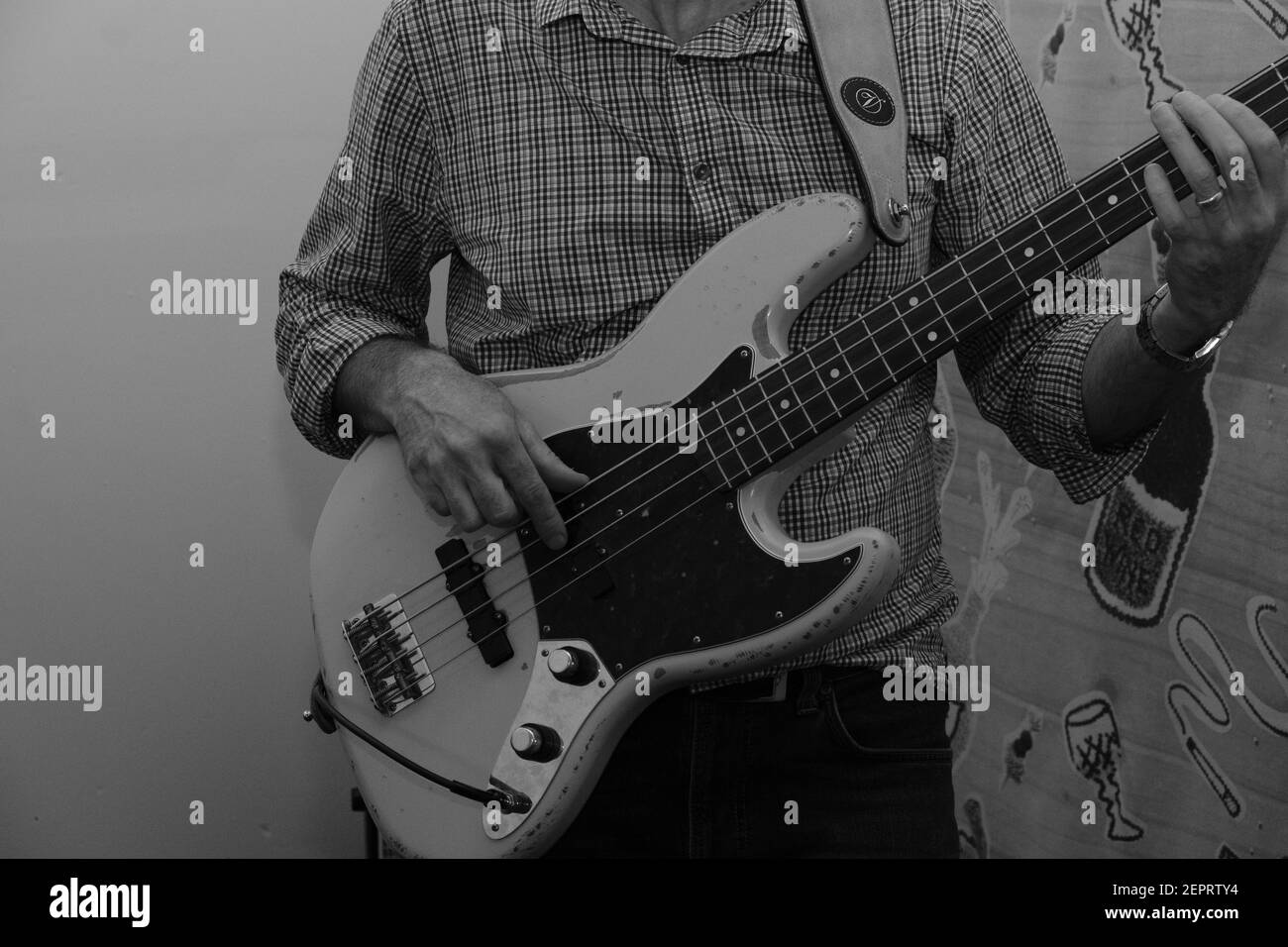 A man playing a Fender Jazz bass guitar in a music rehearsal room Stock Photo