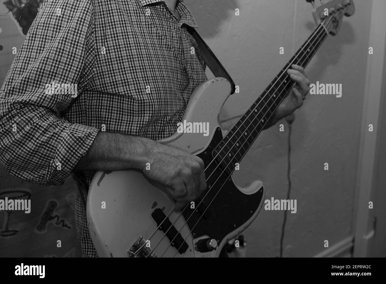 A man playing a Fender Jazz bass guitar in a music rehearsal room Stock Photo
