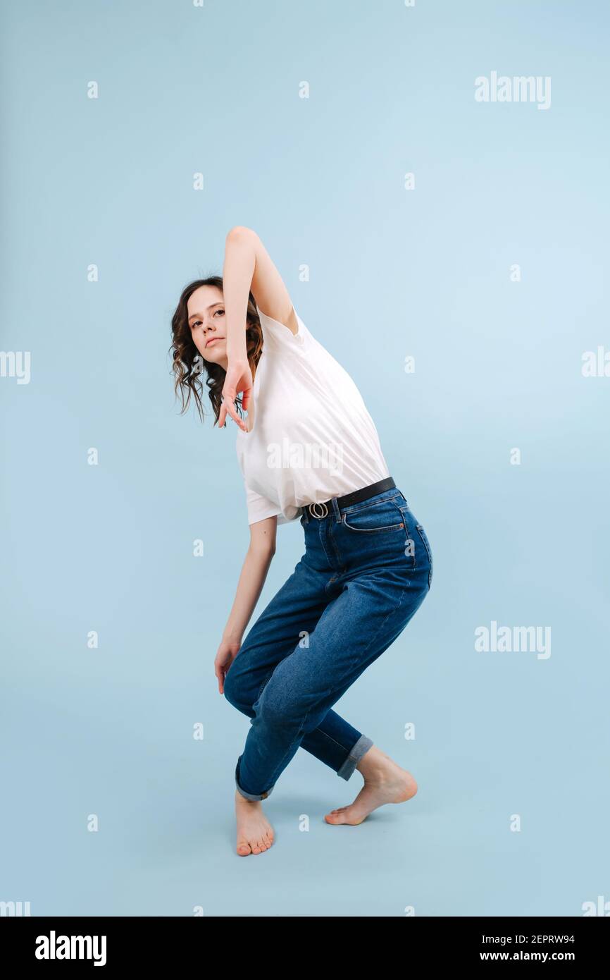 Mindful contemporary dancer poses in front of blue studio background