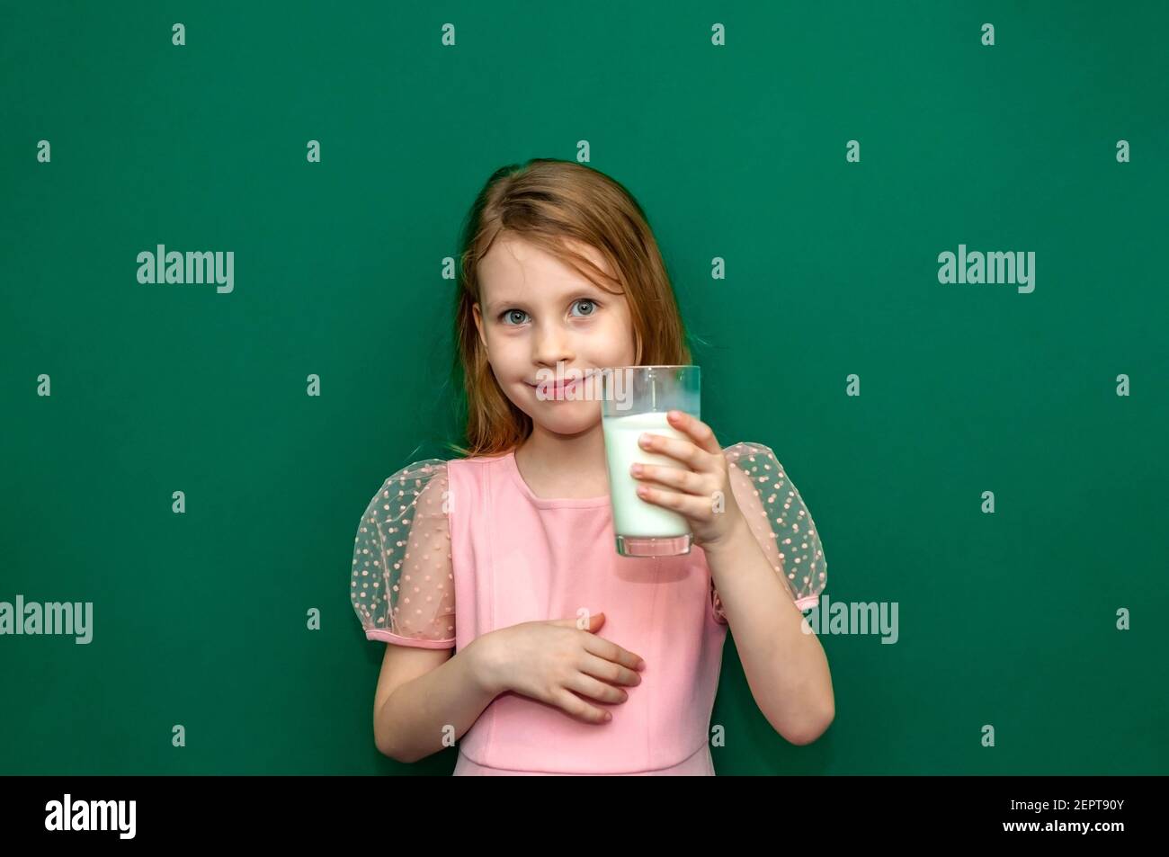 Baby girl holding a glass of milk in her hands Stock Photo