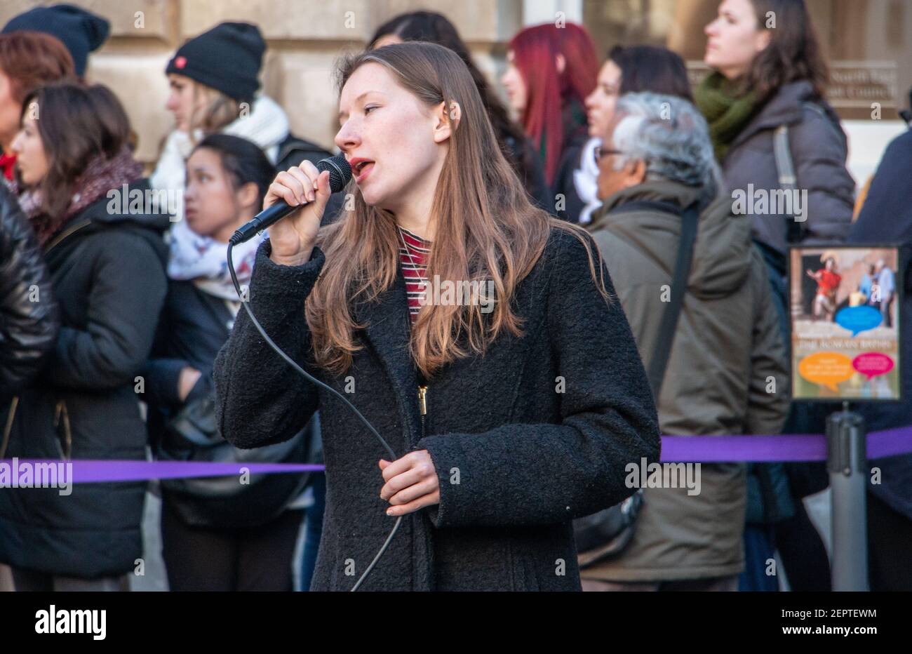 Female singer busking in front of the queue to the Roman Baths, Bath Abbey Church Yard, England, UK Stock Photo
