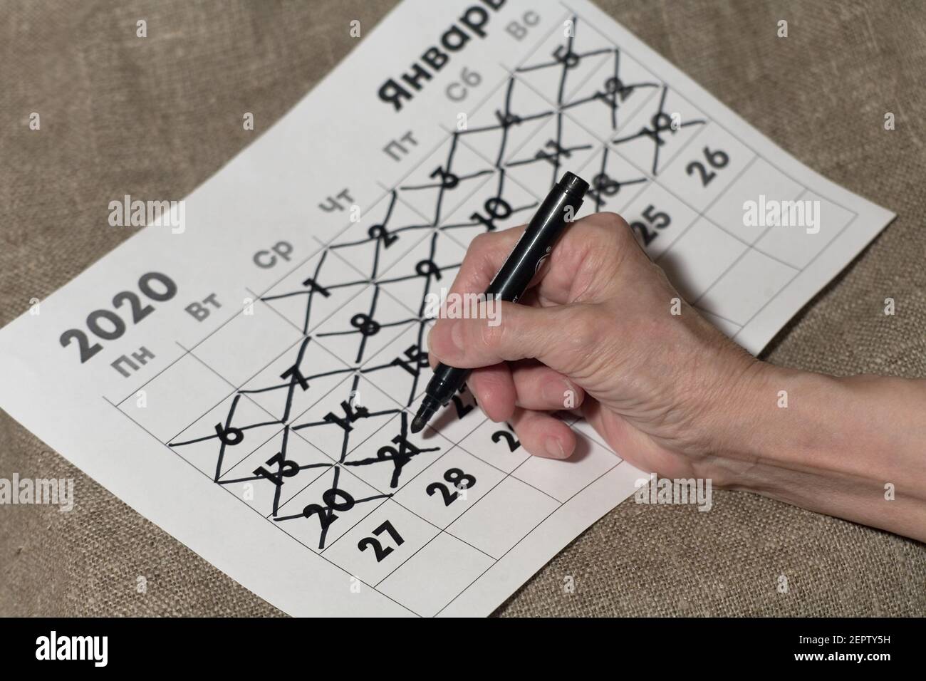 Senile female hand crosses out the number on the calendar with a marker. Close-up. Stock Photo