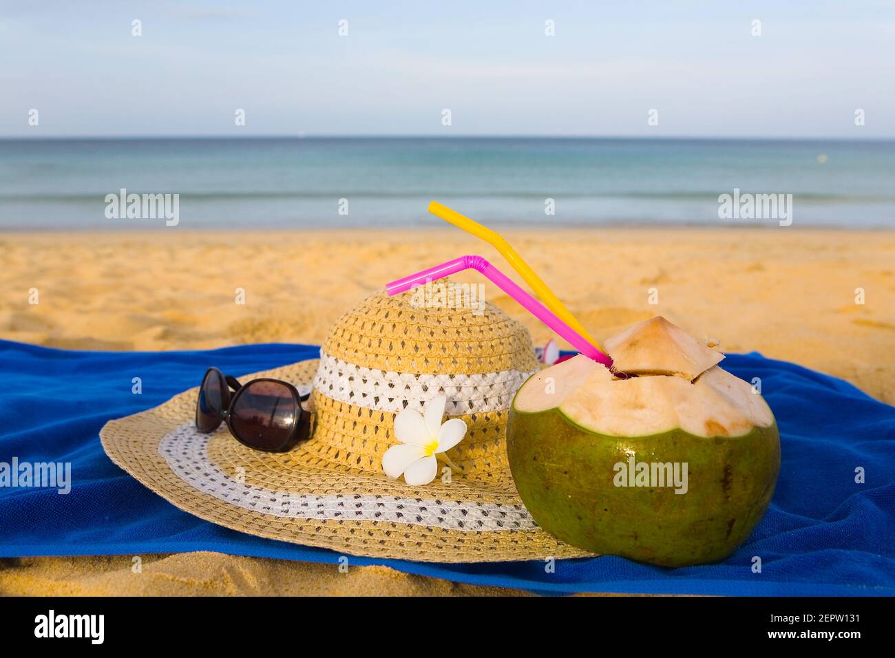 On the sandy beach are sun glasses, a hat and a coconut fruit. Resort. Stock Photo
