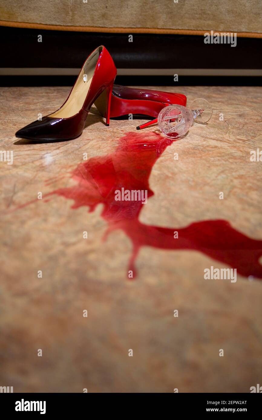 A spilled glass of wine and women's shoes on the floor. Still life. Stock Photo
