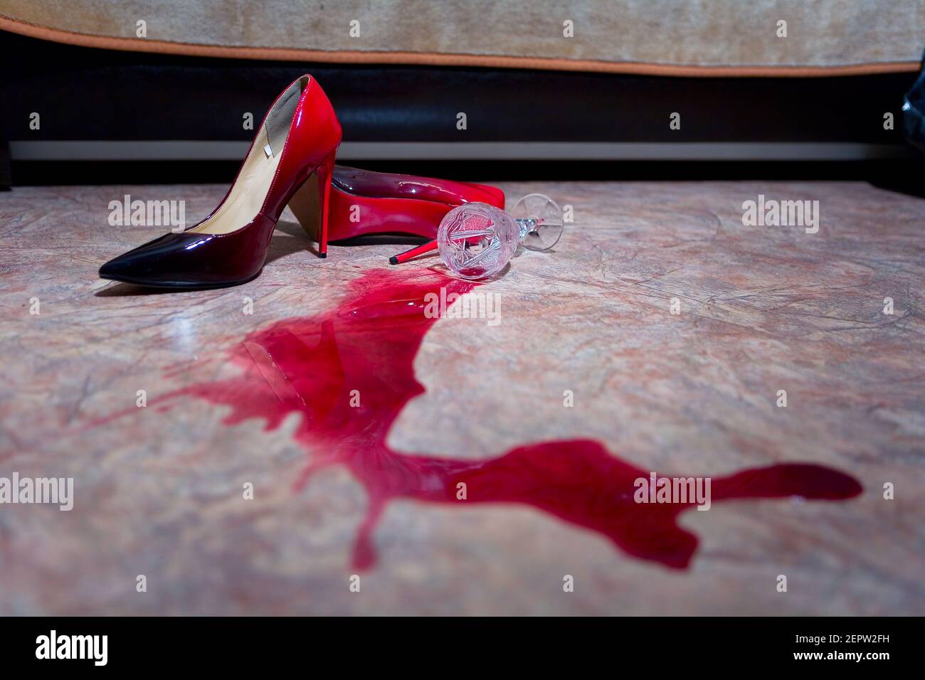 A spilled glass of wine and women's shoes on the floor. Still life. Stock Photo