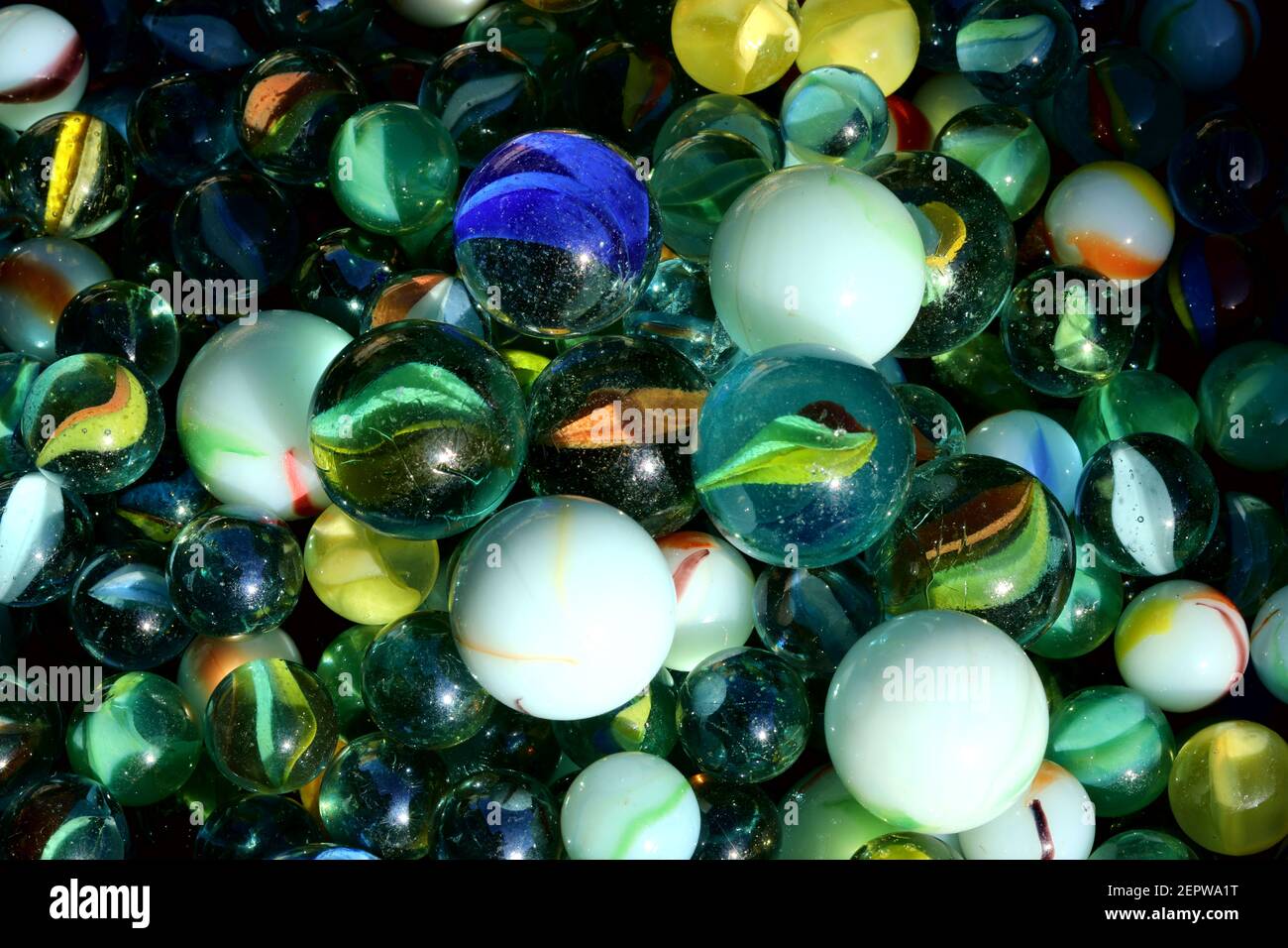 A Big Green Glass Marble Between Yellow Green Blue And Red Marbles On A  Table Stock Photo - Download Image Now - iStock