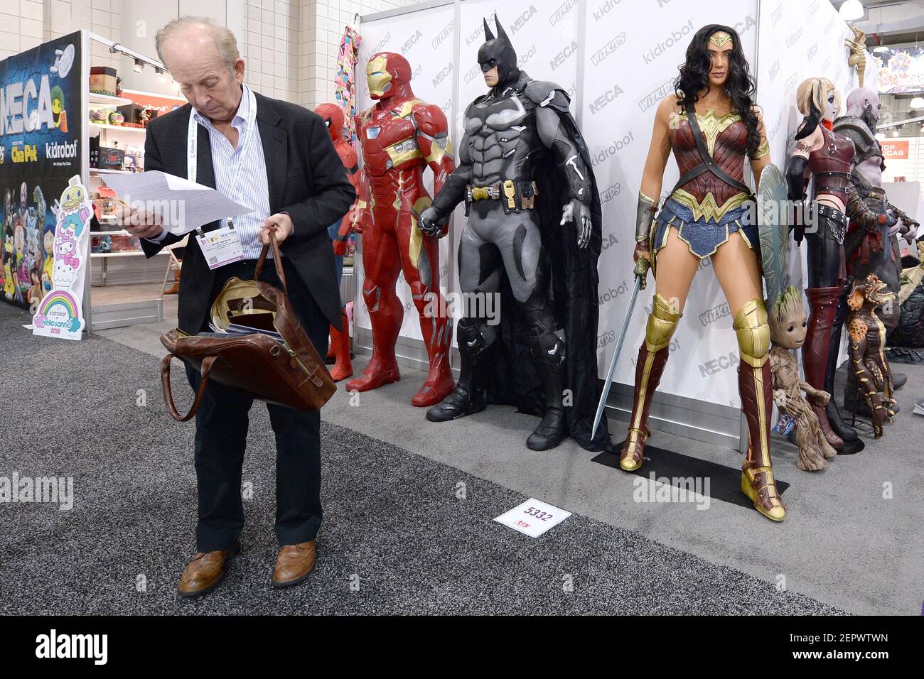 A man stands in front of life size comic book character figures at the